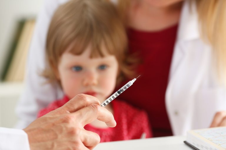little girl staring at vaccine