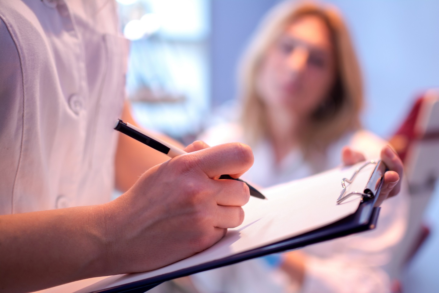 doctor writing on chart as patient looks on