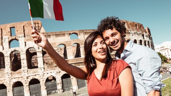Italian couple waving flag Children in Italy Now Can Attend School Without Proof of Vaccination