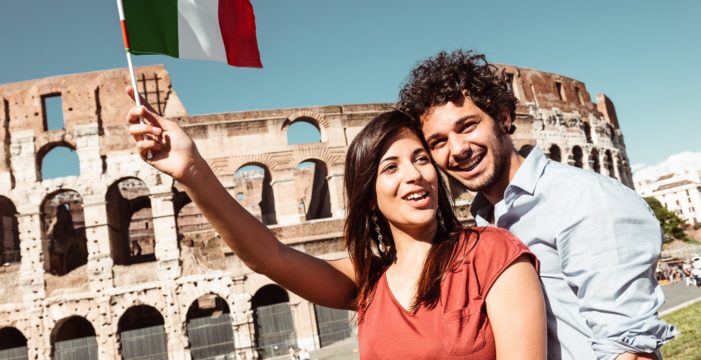 Italian couple waving flag Children in Italy Now Can Attend School Without Proof of Vaccination