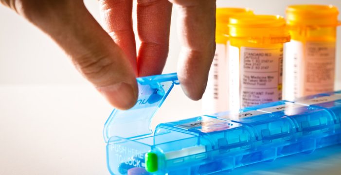 hand reaching for the pill container The Era of Overmedication