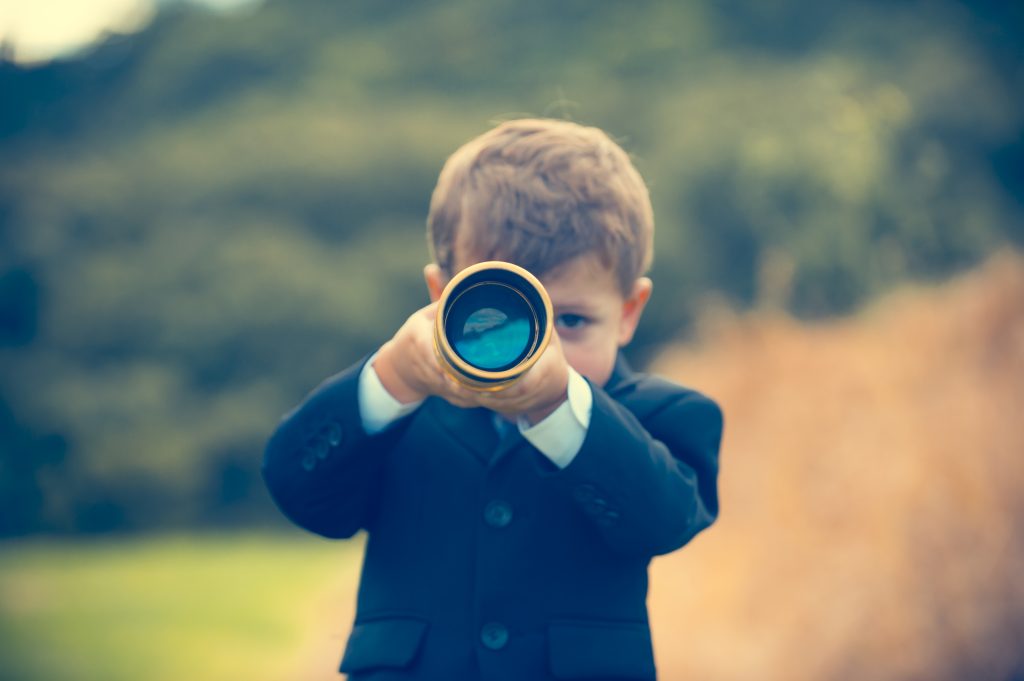 boy in suit looking through telescope