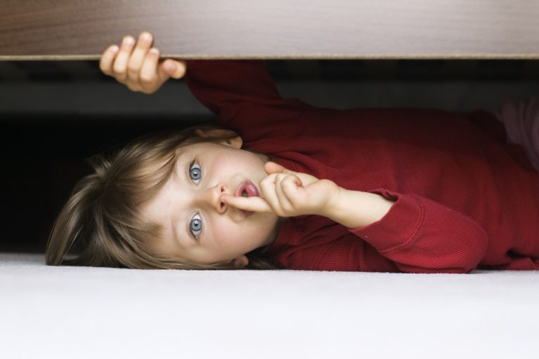 little boy hiding under bed