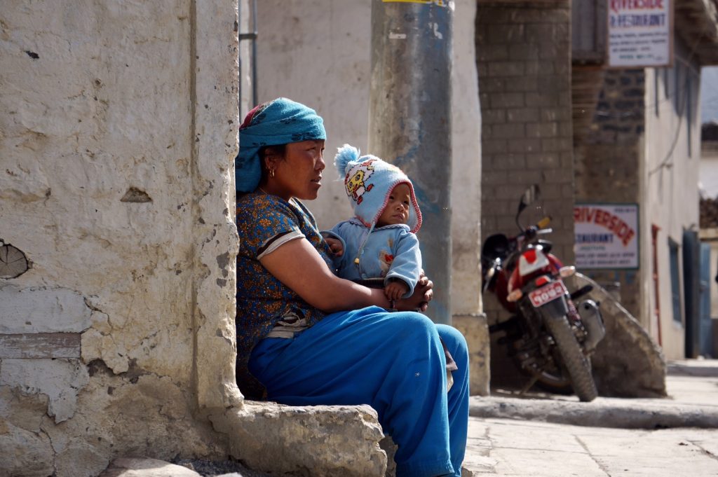 mother and baby sitting along sidewalk in Nepal