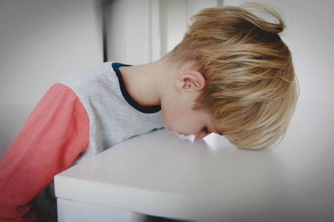 boy resting his head on table