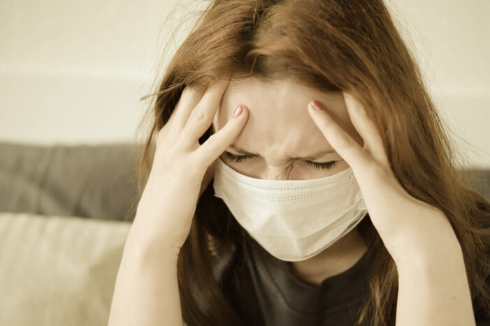masked woman with a headache How is Coronavirus Getting Into the Brain?