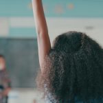 girl in classroom raising her hand