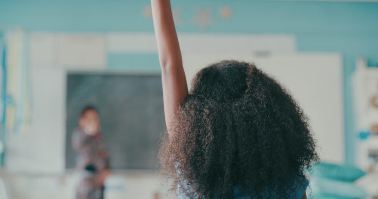 girl in classroom raising her hand