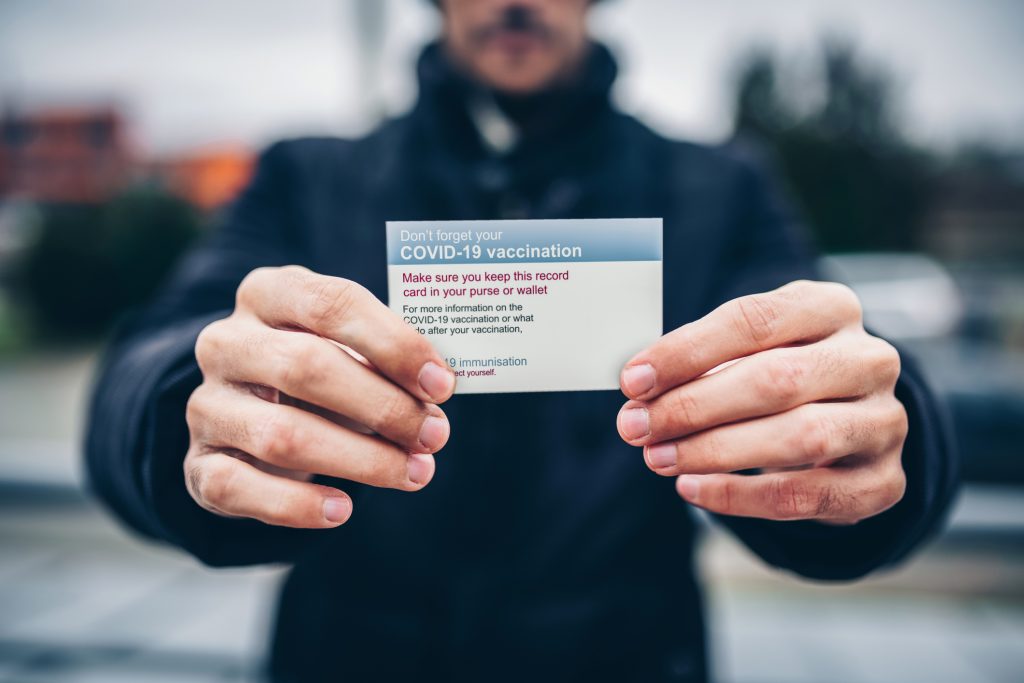 man holding COVID-19 vaccination card