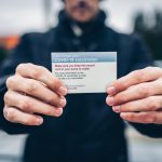 man holding COVID-19 vaccination card