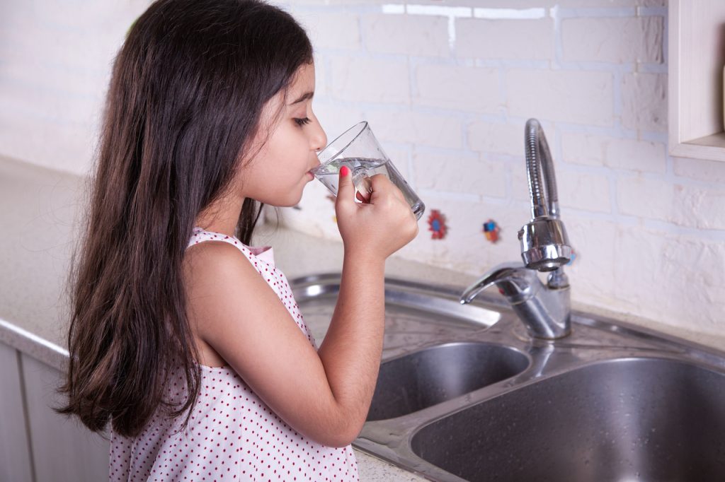 girl drinking faucet water out of glass