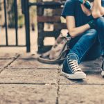 teenage girl sitting on sidewalk