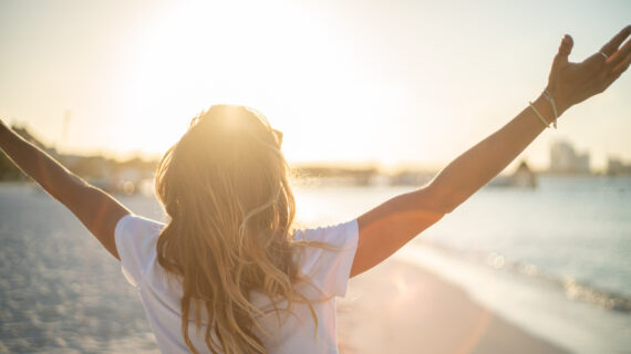 woman on beech embracing sunlight Why Is There Such Reluctance to Discuss Natural Immunity?