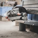 homeless man sleeping on bench
